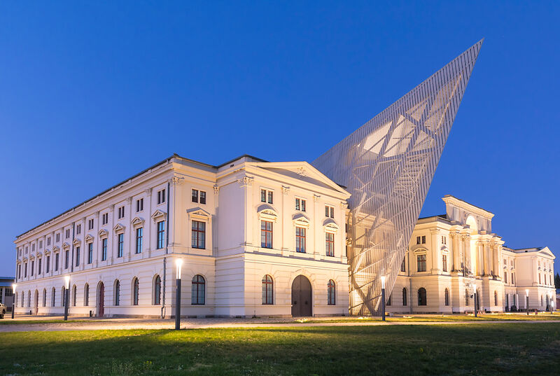 Das Militärhistorische Museum Dresden bei Nacht – die eindrucksvolle Architektur des Daniel-Libeskind-Baus erstrahlt in der Abendbeleuchtung. Ein Ort, der Geschichte und moderne Architektur vereint und zum Nachdenken anregt. Foto: Thomas Rötting (DML-BY) --- The Dresden Military History Museum by night - the impressive architecture of the Daniel Libeskind Building shines in the evening light. A place that combines history and modern architecture and is thought-provoking. Photo: Thomas Rötting (DML-BY)